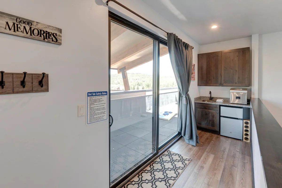 A welcoming kitchenette area with a sliding glass door that leads outside, adorned by a 'Good Memories' sign, curtains, and natural light flooding in. The sliding door serves as a literal and symbolic threshold between the home and outdoor adventures.