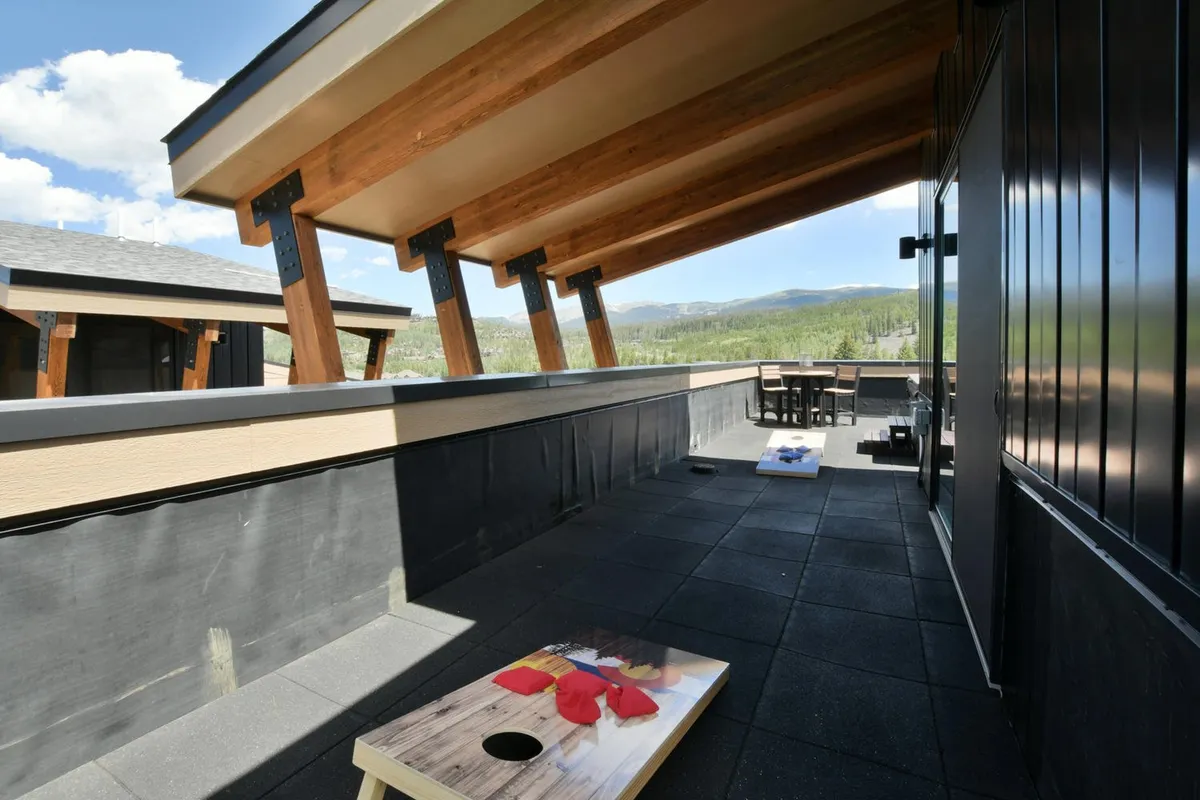 An inviting outdoor seating area with a cornhole game set up, comfortable chairs, and stunning mountain views in the background. The space encourages social interaction and outdoor enjoyment, while the scenery connects the home to its natural surroundings.