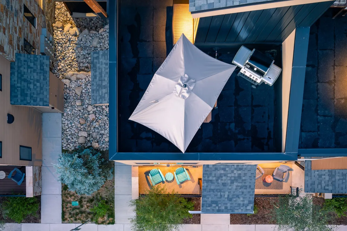 This image captures a cozy and inviting outdoor seating area with a grill and umbrella, perfect for barbecuing, relaxing, or enjoying evening chats under the stars. The seating arrangement and atmosphere suggest a comfortable spot for socializing or unwinding after seasonal adventures.