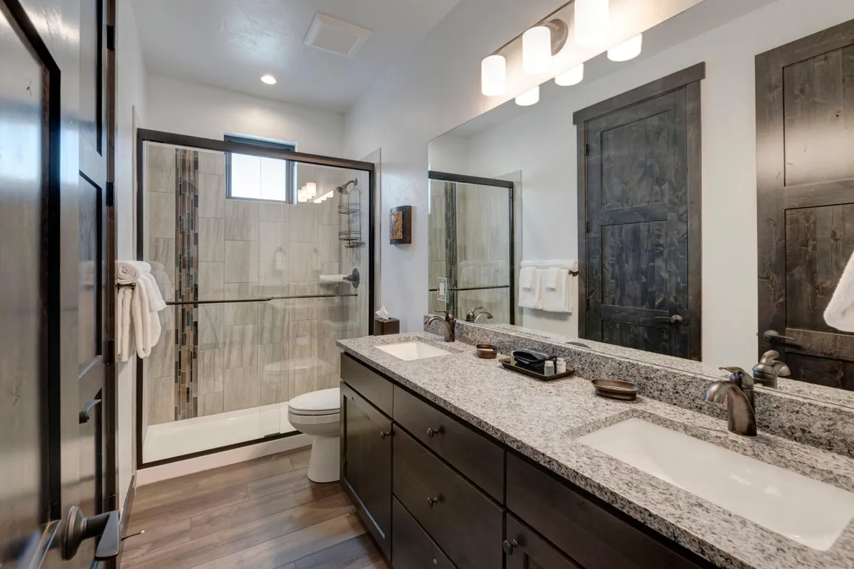 A spacious spa-inspired bathroom with a double vanity, walk-in shower, and mirrored cabinetry. The tranquil, inviting ambiance encourages relaxation and provides a luxurious self-care experience.